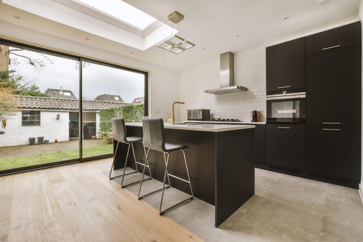 The interior of a cozy kitchen with a breakfast bar and modern equipment in dark colors in a residential apartment